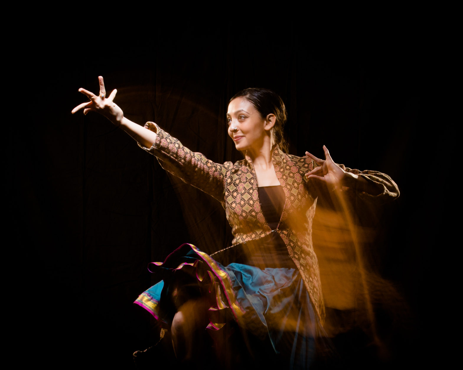Gandini Juggling dance pro-shot with one hand at her chest, the other extended out