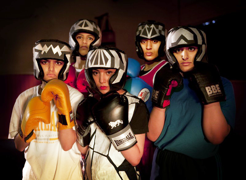 a formation of five girls all with headgear and boxing gloves on looking sternly at the camera
