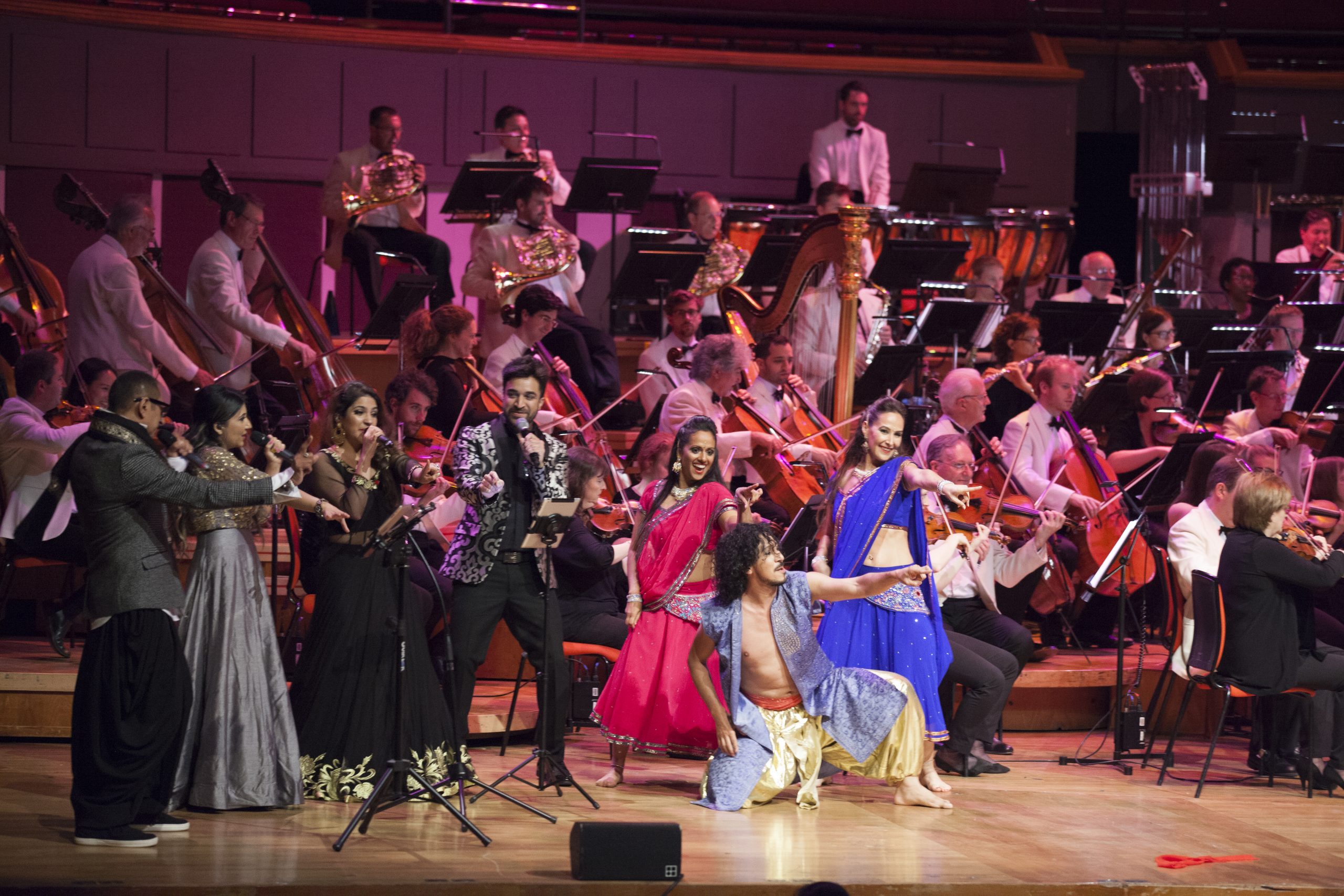 Bollywood singers, and dancers perform in front of a full live orchestra