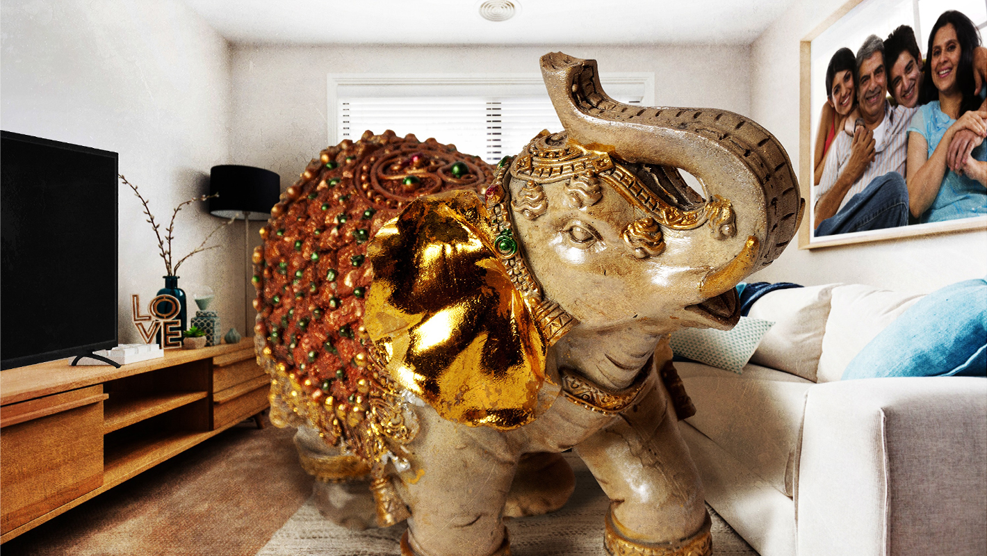 A large gold stone elephant ornament overtakes a homely living room with a family portrait on the right wall