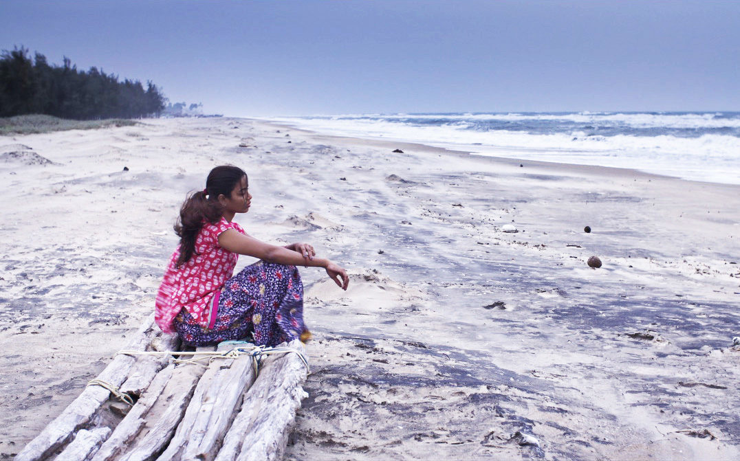 At the sea front, a girl dressed in pink top and patterned trousers sat on the raft