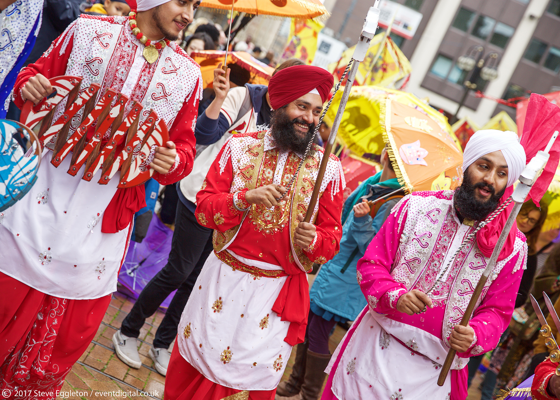 Colourfully dressed Bhangra group smiling surrounded by community and colour