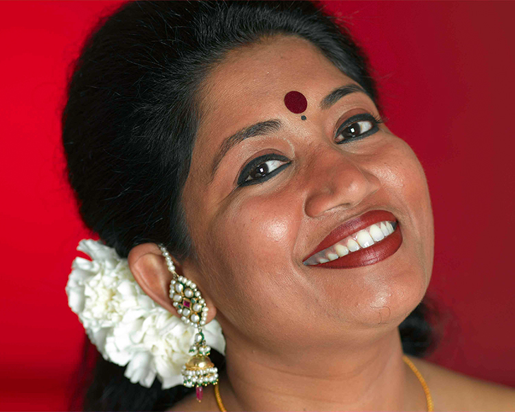 Sanchita Pal close up against red background smiling