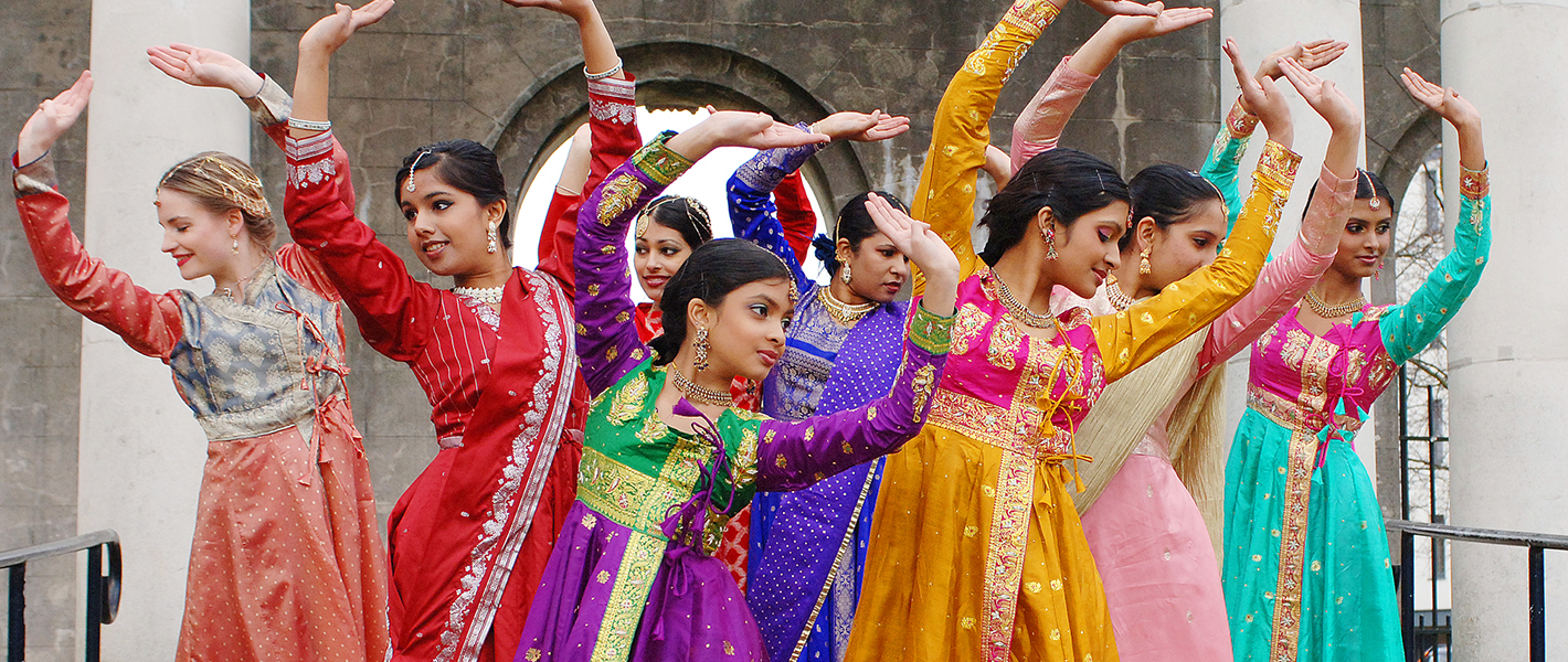 A celebration of colour in a group of women in and girls in brightly coloured Punjabi suits holding a formation in an outdoor setting