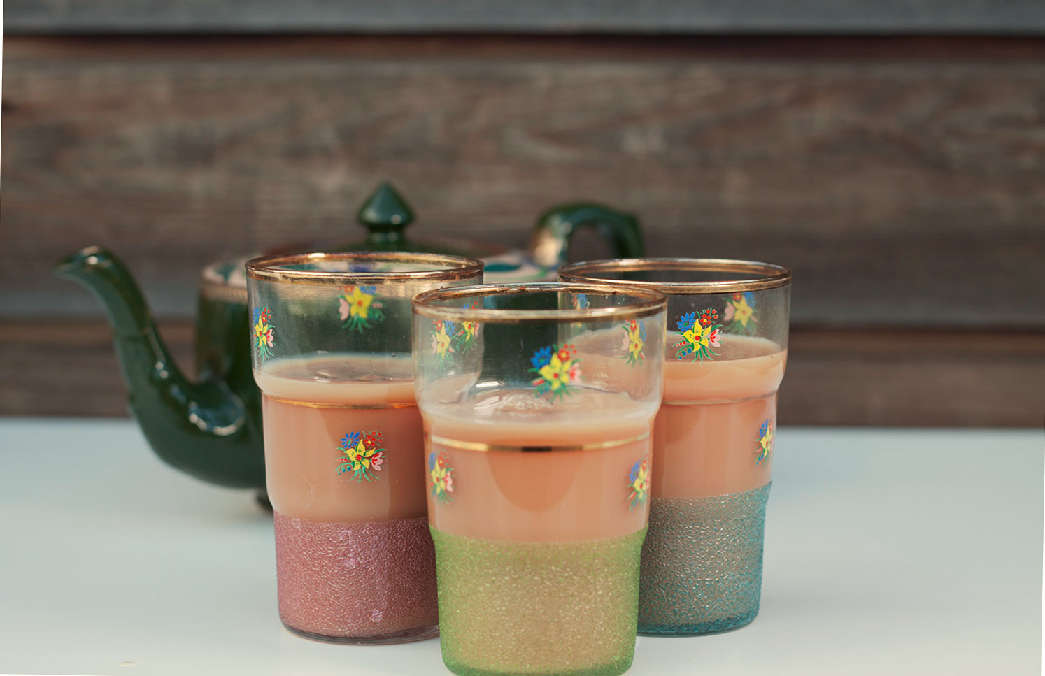 three multicoloured glasses of chai