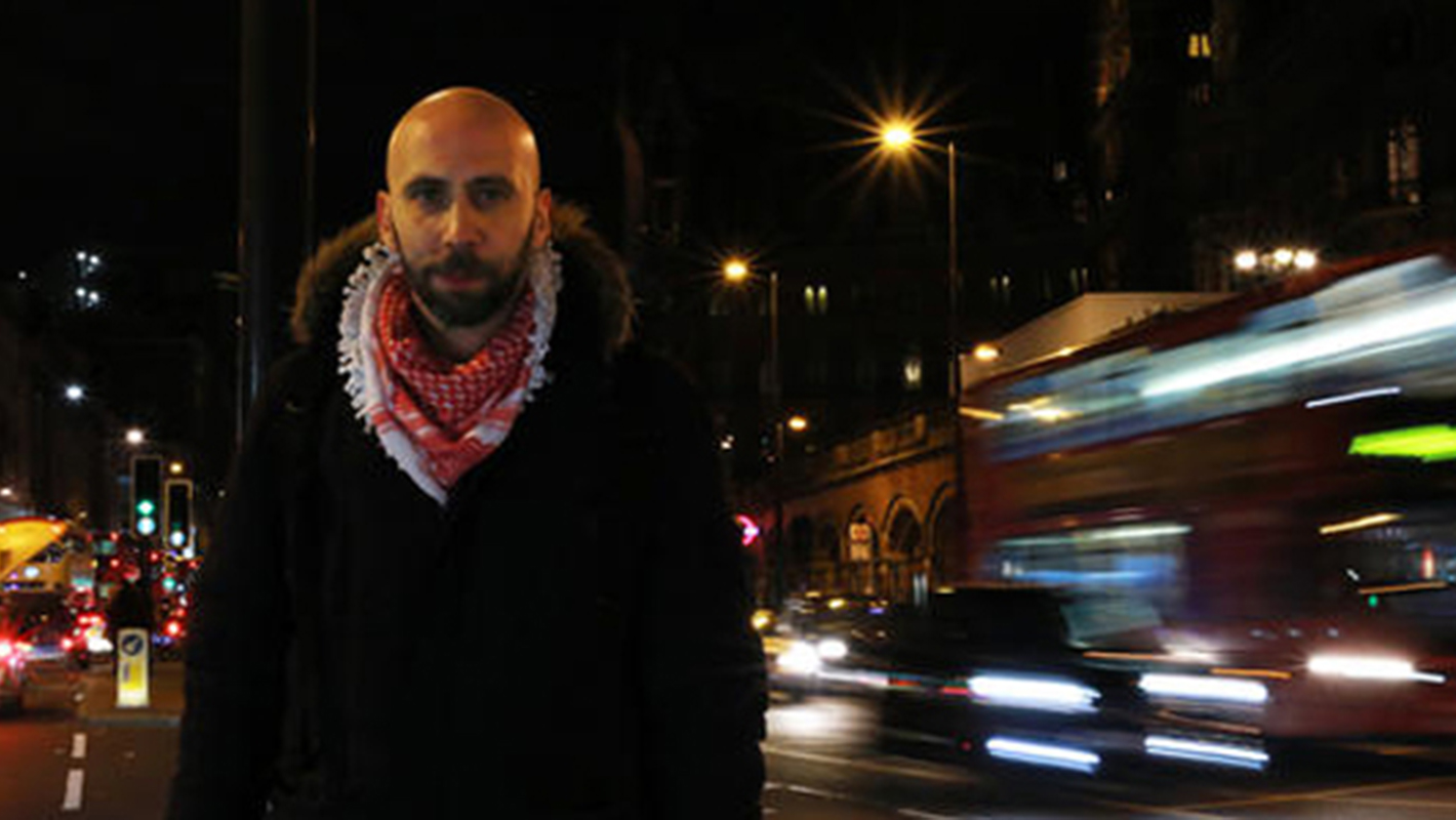 A man stands in focus with the bustling city that flashes past behind him