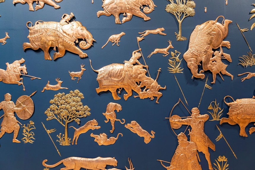 bronze artwork against a blue background