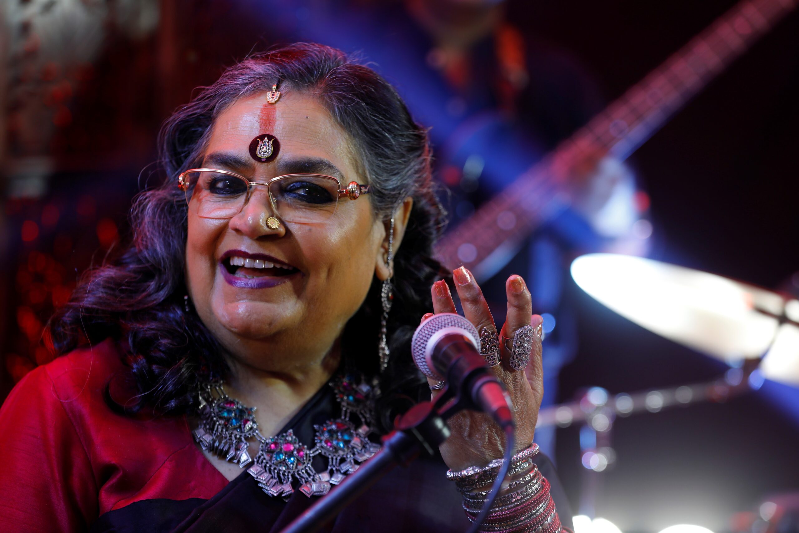 Usha Uthup smiling and singing to the camera