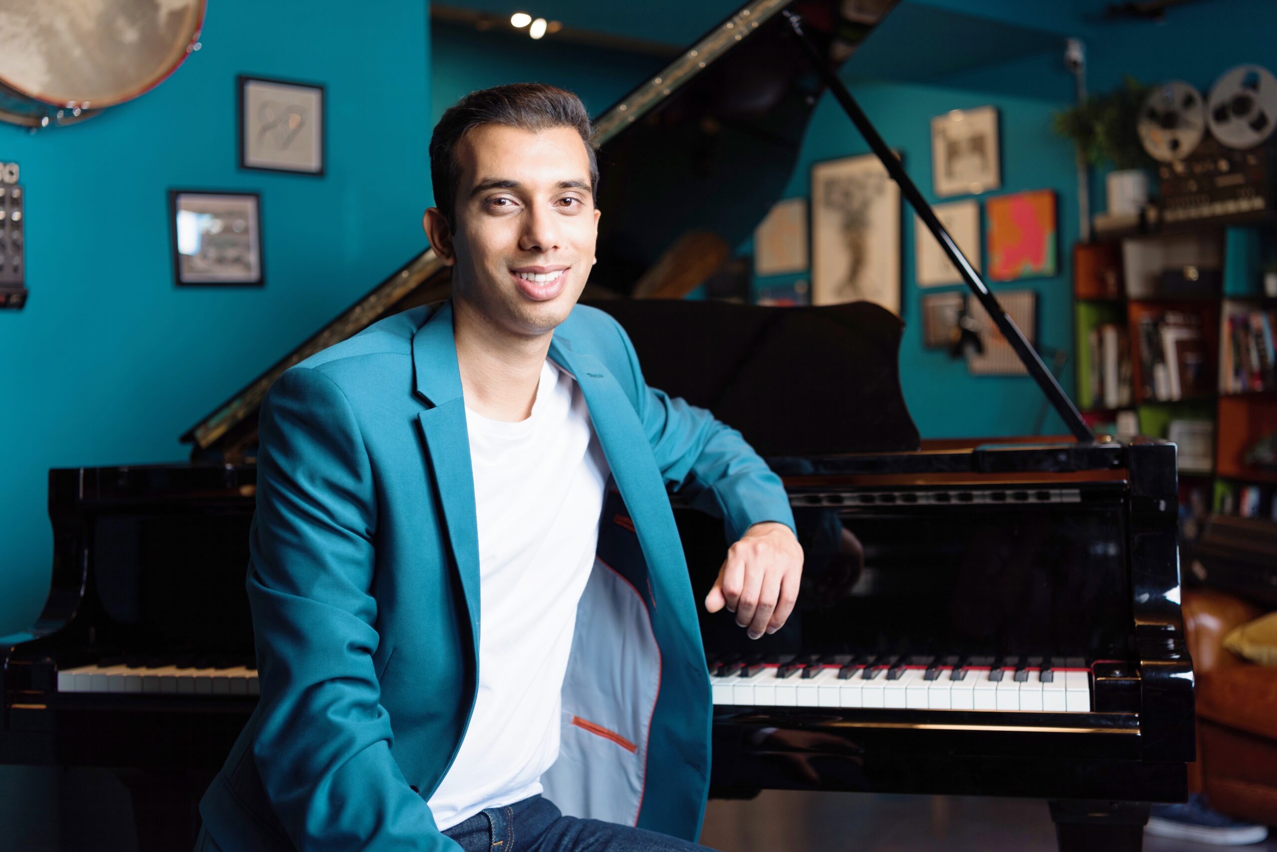 Man in blue suit sat in front of a piano