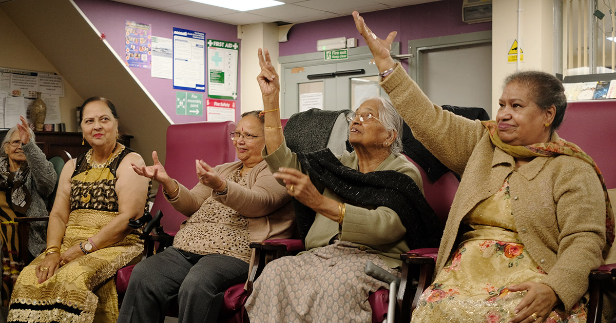 a group of older women participating with their hands up
