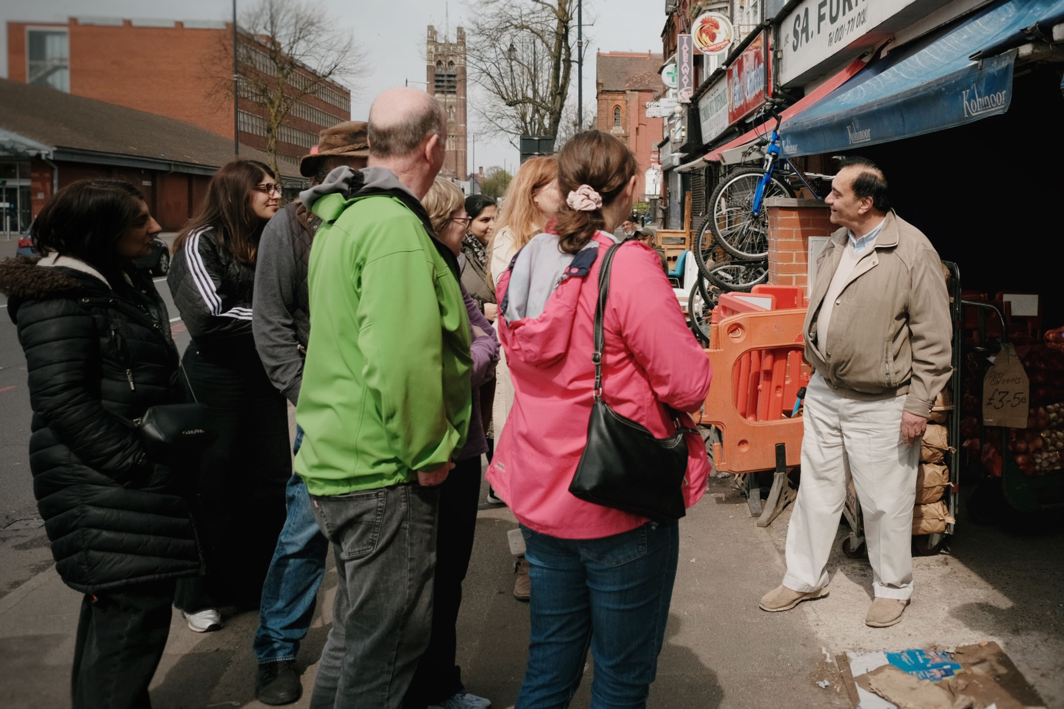A group of people talking to a shop keeper