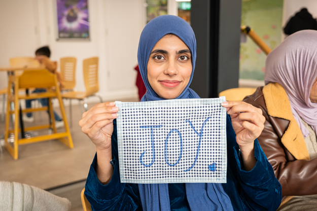Lady holding a piece of material that says Joy